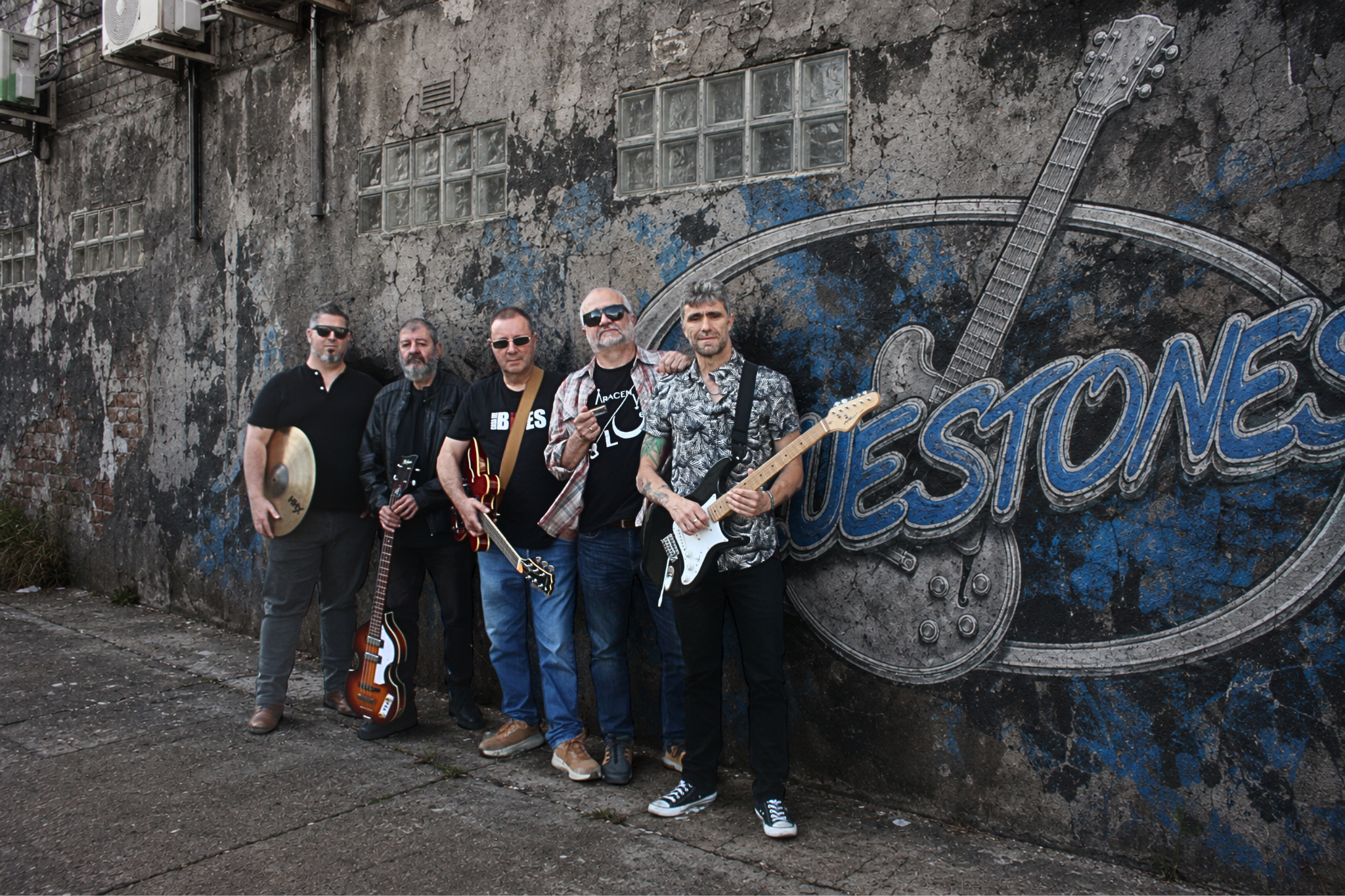 Los Bluestones junto a un mural urbano con el logotipo de la banda